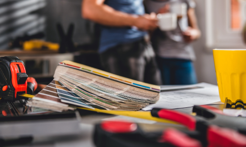 Power tools laid across a table with a blurred couple standing in the background
